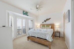 A bedroom with a bed, a ceiling fan, a wall-mounted fish decoration, and a 'Hello' sign.