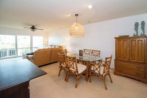 A dining area with a round table and chairs, a ceiling fan, a wooden cabinet, and a sofa.