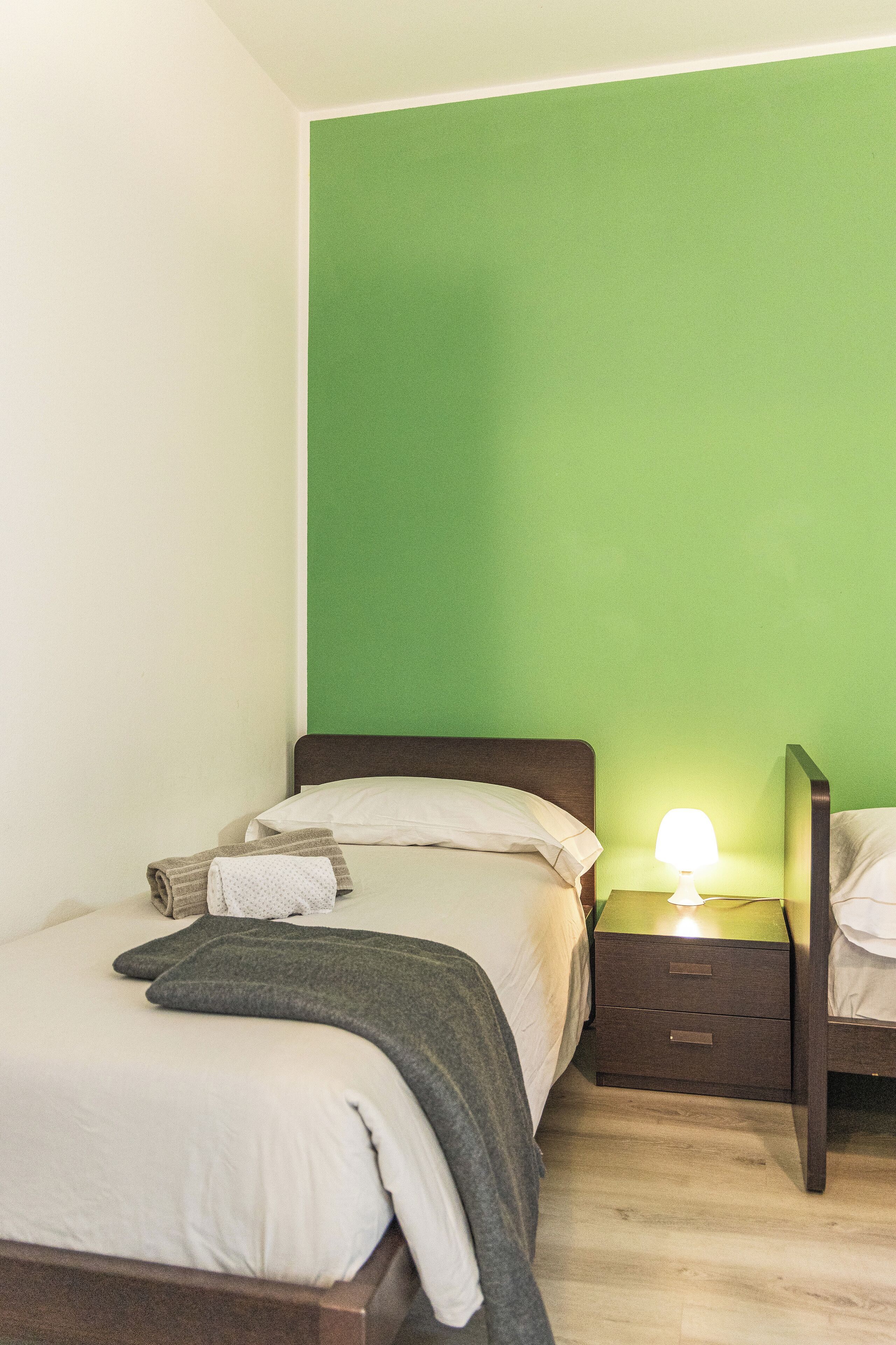 Une chambre à coucher avec un lit, une table de chevet avec une lampe et un mur vert.