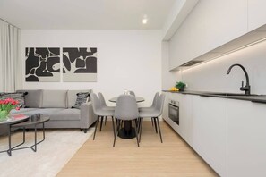 Une cuisine moderne avec un coin repas, un canapé et des œuvres d’art abstraites accrochées au mur.