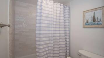 A bathroom with a shower curtain, a toilet, and a painting on the wall.