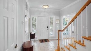 A hallway with white doors, a wooden bench, a striped rug, and a staircase with wooden railings.