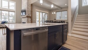A modern kitchen with a large island, stainless steel appliances, and a stone accent wall. - 103 Travertine Trail - New Build - Managed by Purgatory Resort (Durango)
