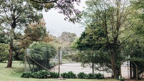 Un espace vert clôturé, agrémenté d’arbres et doté d’un sentier menant à une porte.