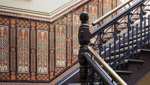 Una escalera con intrincados diseños de azulejos y barandilla de metal negro.