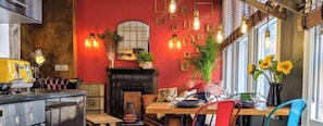 Ein Essbereich mit roter Wand, Kamin und Tisch für zwei Personen.