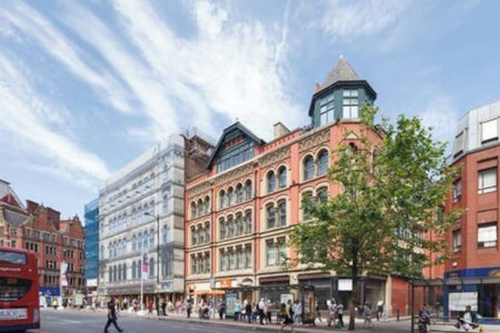 A street with historic buildings, a bus, and pedestrians.