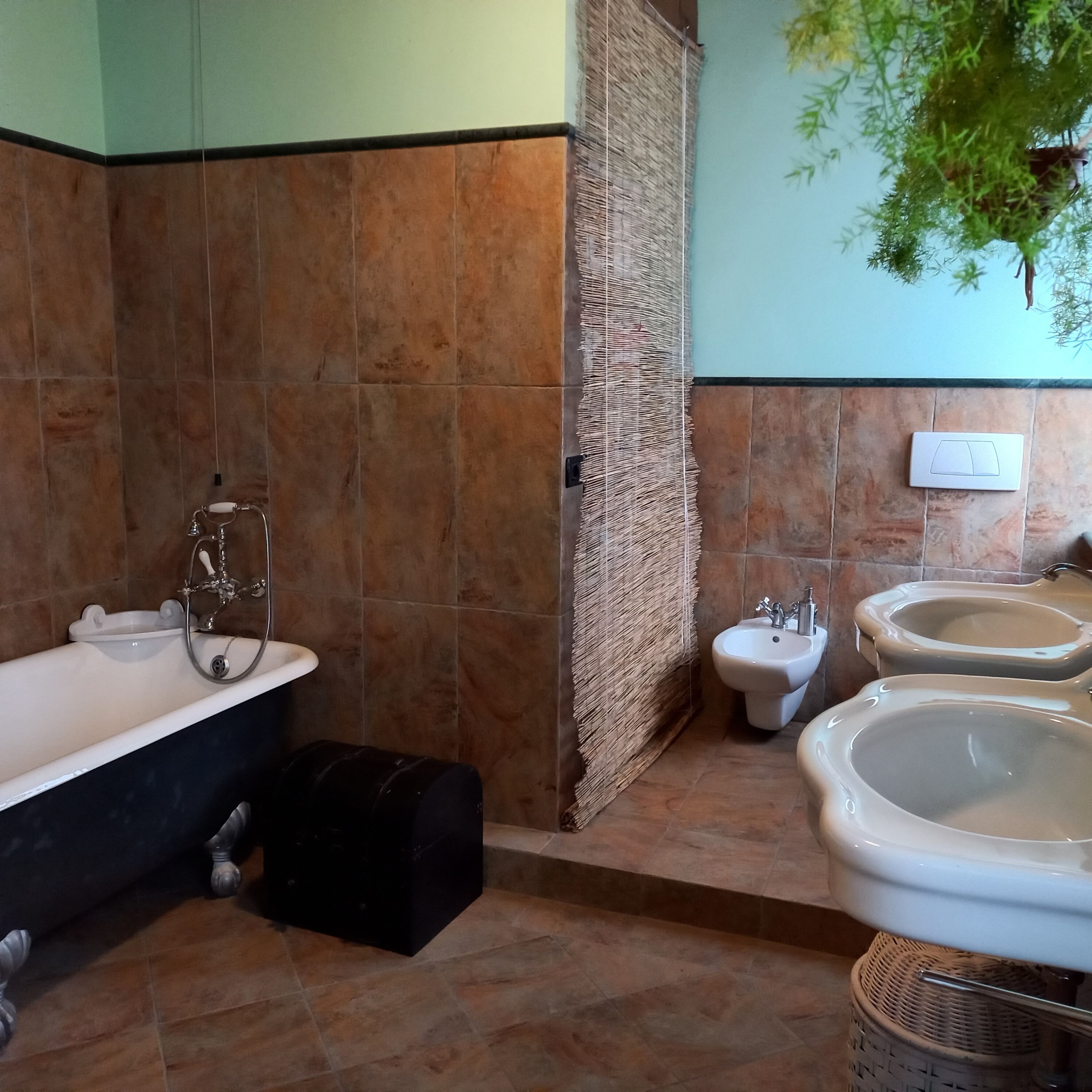 Een badkamer met een badkuip, een toiletbril en twee wasbakken.