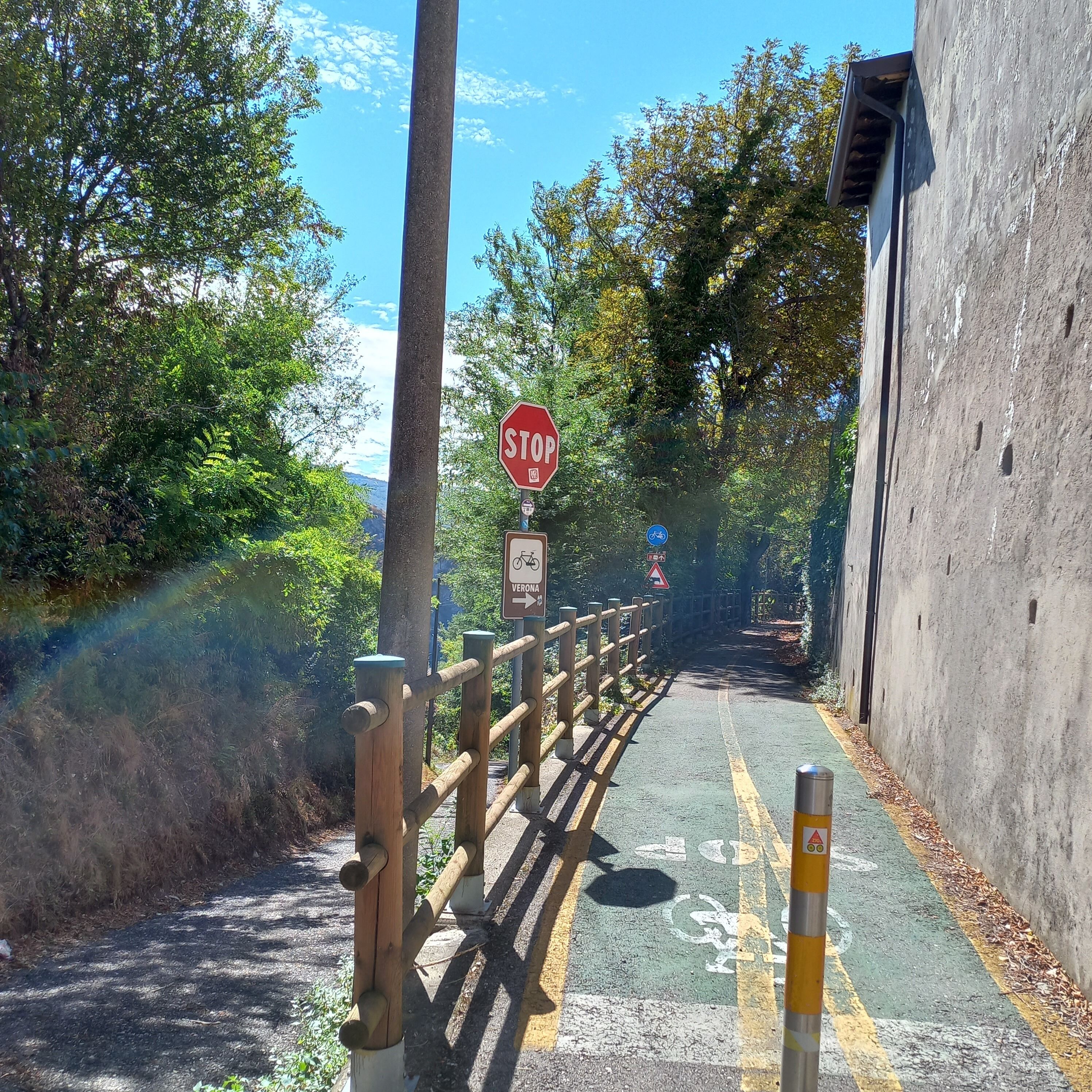 A road with a stop sign, a bicycle lane, and a wooden fence.