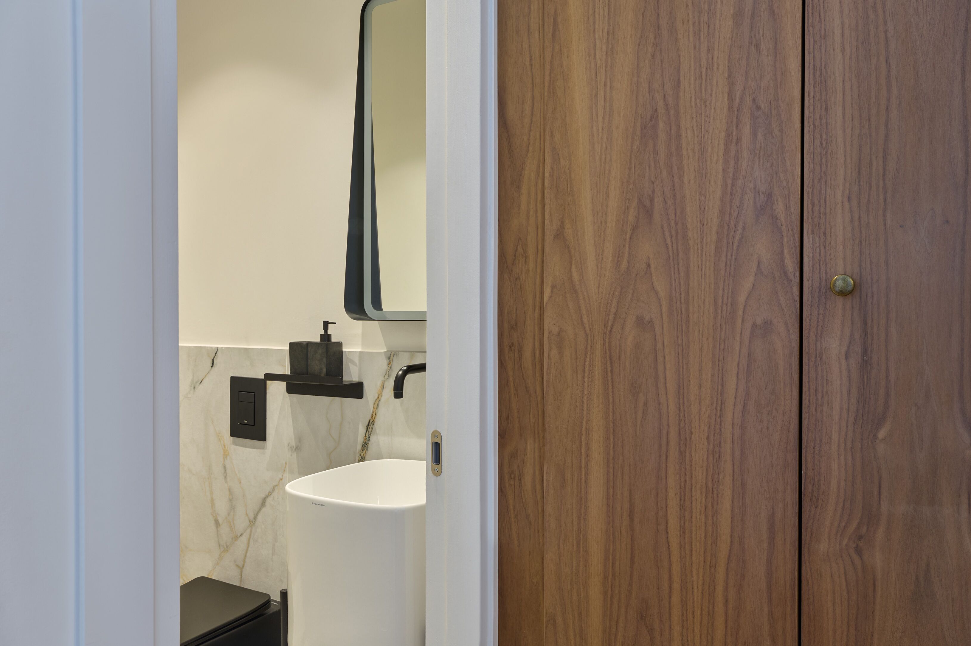 A bathroom with a white sink, a mirror, and a wooden door.