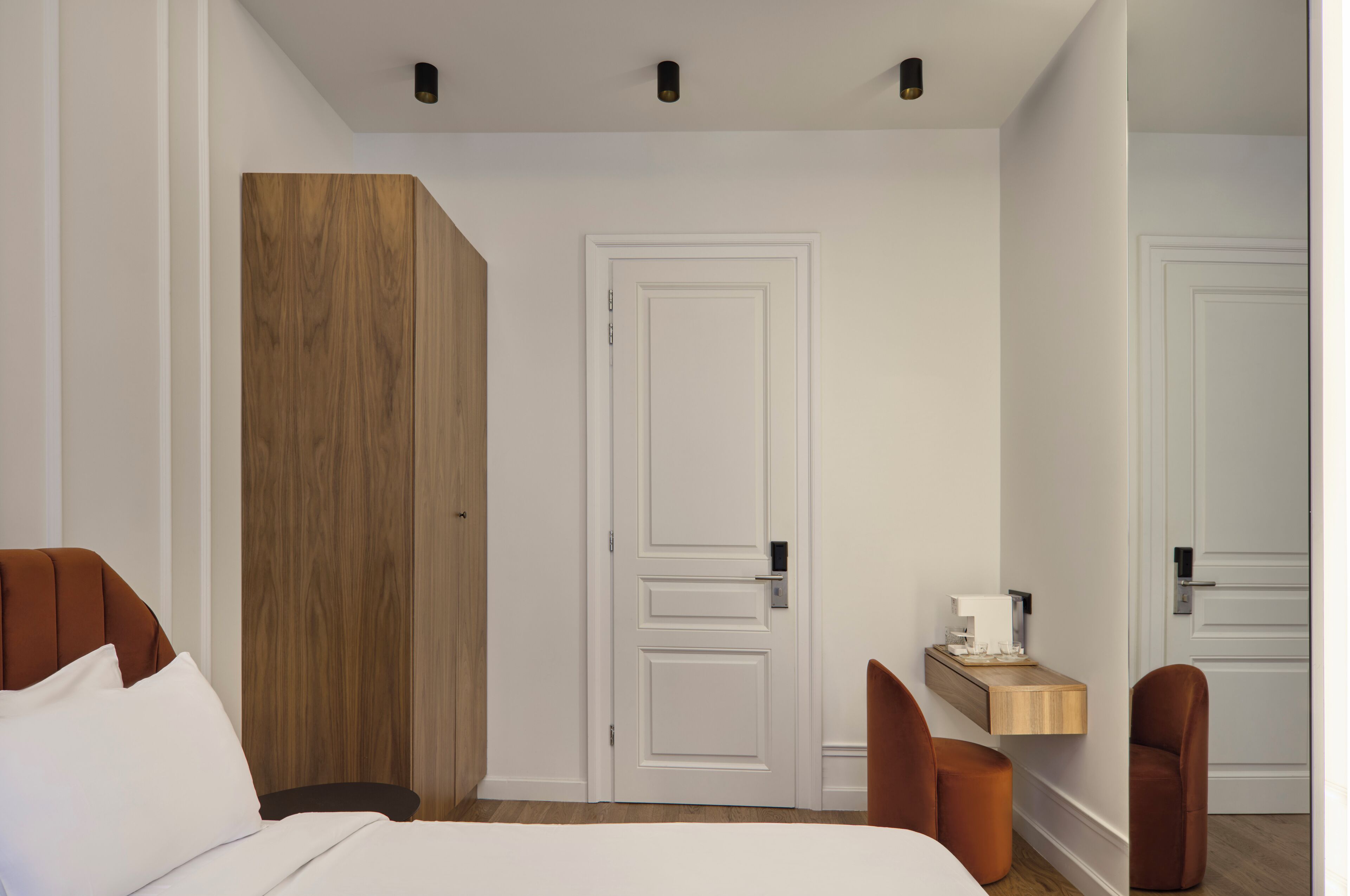 Ein Hotelzimmer mit Bett, einem Holzschrank, einer weißen Tür und einem kleinen Holzboden mit Taschentuchbox.