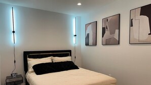 A modern bedroom with a bed, bedside tables, and abstract wall art. - Stay in Style & Elegance (Burbank)