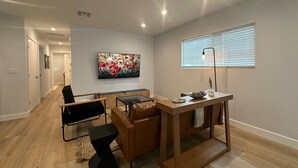 A modern living room with a dining area, a large painting on the wall, and a window with blinds. - Stay in Style & Elegance (Burbank)