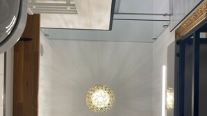 A modern interior with a central chandelier, white walls, and a wooden door.