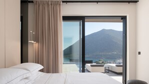 Un dormitorio moderno con una cama grande, una puerta corrediza de vidrio que da a un balcón con vistas a la montaña.