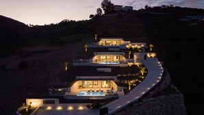 Una casa moderna de varios niveles con piscina, sendero de piedra e iluminación exterior.
