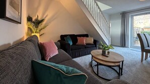 A modern living room with a grey sofa, a round coffee table, and a staircase leading to a balcony.