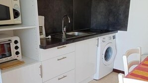Eine kleine Küche mit Mikrowelle, Toaster, Spüle und Waschmaschine.