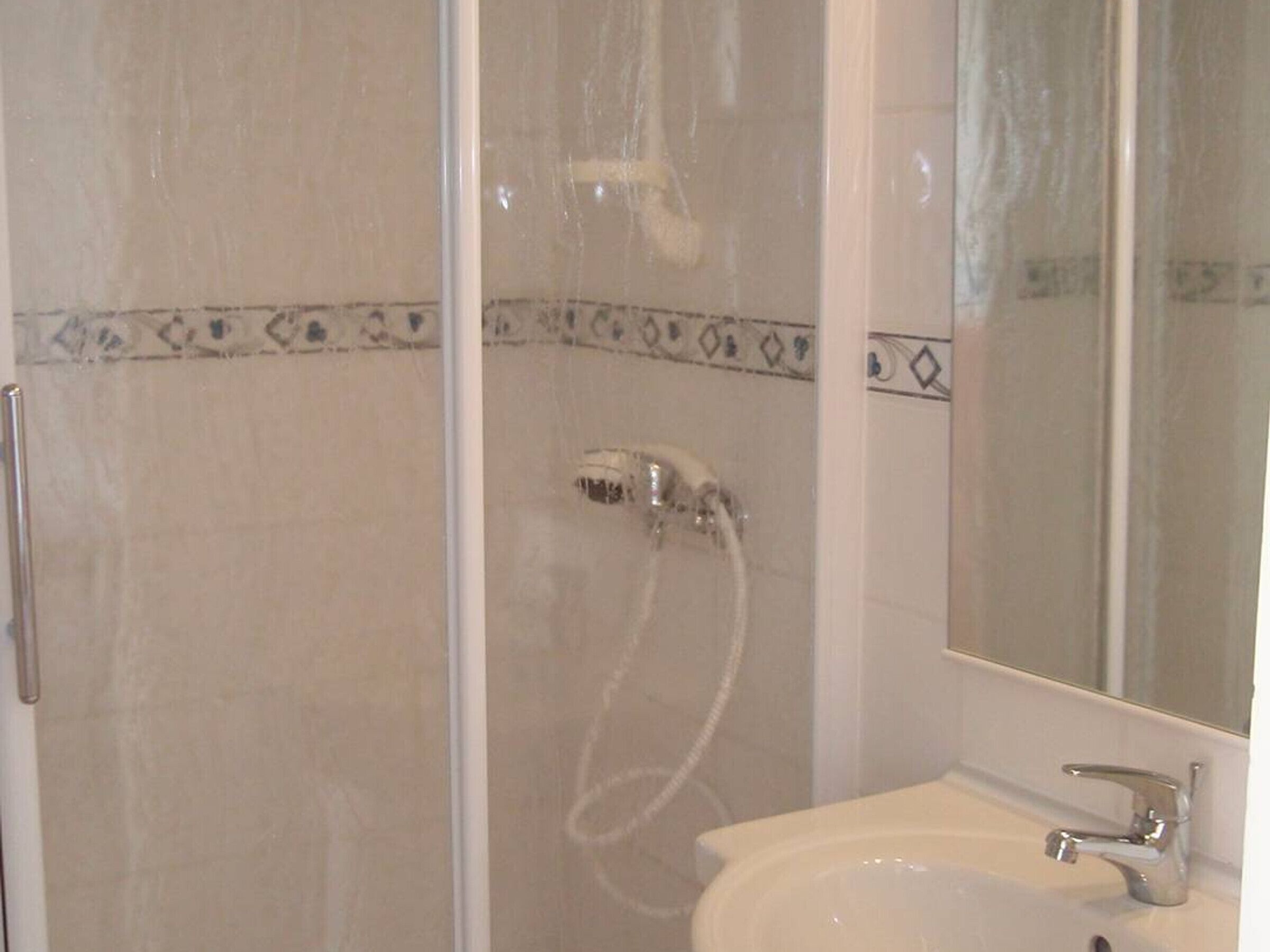 Une salle de bain avec une douche, un lavabo et un miroir.