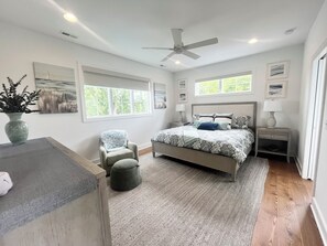 A bedroom with a bed, a chair, a nightstand, a lamp, a vase, and a window. - Beautiful home with private pool! (Rehoboth Beach)