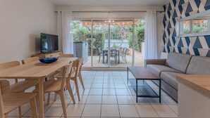 A modern living room with a dining area, a sofa, and a TV. - Renovated 2-Bed Apt in Biscarrosse Plage, Sleeps 4, Ocean View Terrace, Pet-Friendly (Biscarrosse Plage)