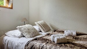 A bedroom with a bed, pillows, a lamp, and a window.