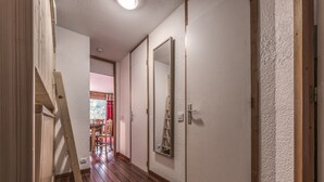 A hallway with wooden flooring, a wooden ladder, and a large mirror on the wall.