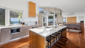 Una cocina moderna con una isla central, ventanas amplias y una pared de acento de piedra.