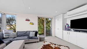 Una sala de estar moderna con un sofá, un tapete de cuero de vaca y un televisor de pantalla plana montado en la pared.