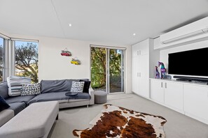 A modern living room with a sofa, a cowhide rug, and a flat-screen TV mounted on the wall. - Sandbanks (Separation Creek)