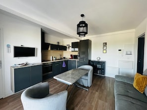 A modern kitchen with a TV, cabinets, and a dining area with a table and chairs.