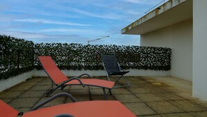 Un área de estar al aire libre con sillones rojos y una pared blanca.