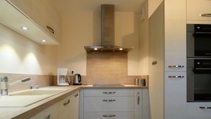 Una cocina moderna con un lavamanos doble, una cafetera, una estufa empotrada y un refrigerador de acero inoxidable.