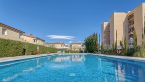A swimming pool surrounded by apartment buildings, with clear skies and a calm water surface. - Superbe Maison de Vacances à Santa Margarita Immo365 (Roses)