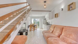 A modern living area with a staircase, a sofa, a dining table, and a kitchen in the background. - Superbe Maison de Vacances à Santa Margarita Immo365 (Roses)