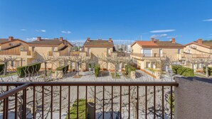 A residential area with uniform beige houses, a clear blue sky, and a paved walkway with trimmed shrubbery. - Superbe Maison de Vacances à Santa Margarita Immo365 (Roses)