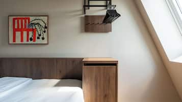 A bedroom with a wooden headboard, a bed, a wall-mounted shelf with books, and a framed artwork.