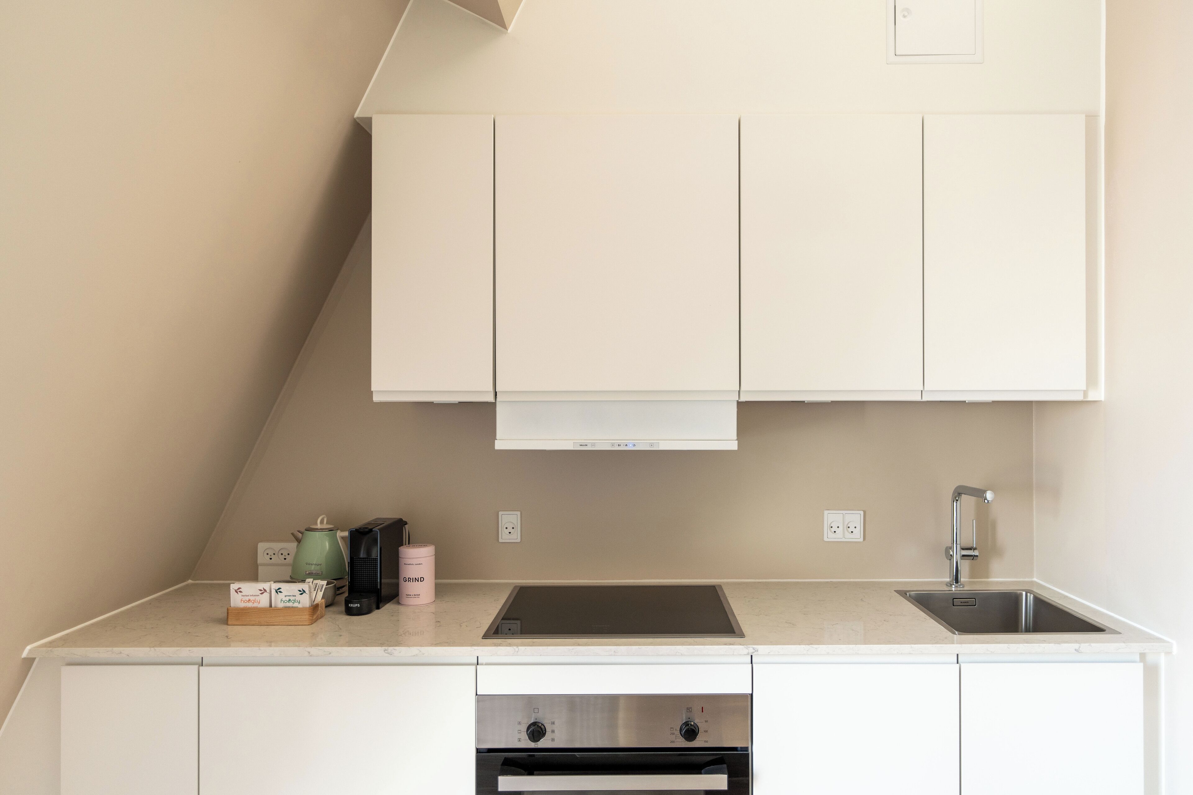 A modern kitchen with white cabinets, a stainless steel sink, and a built-in oven.