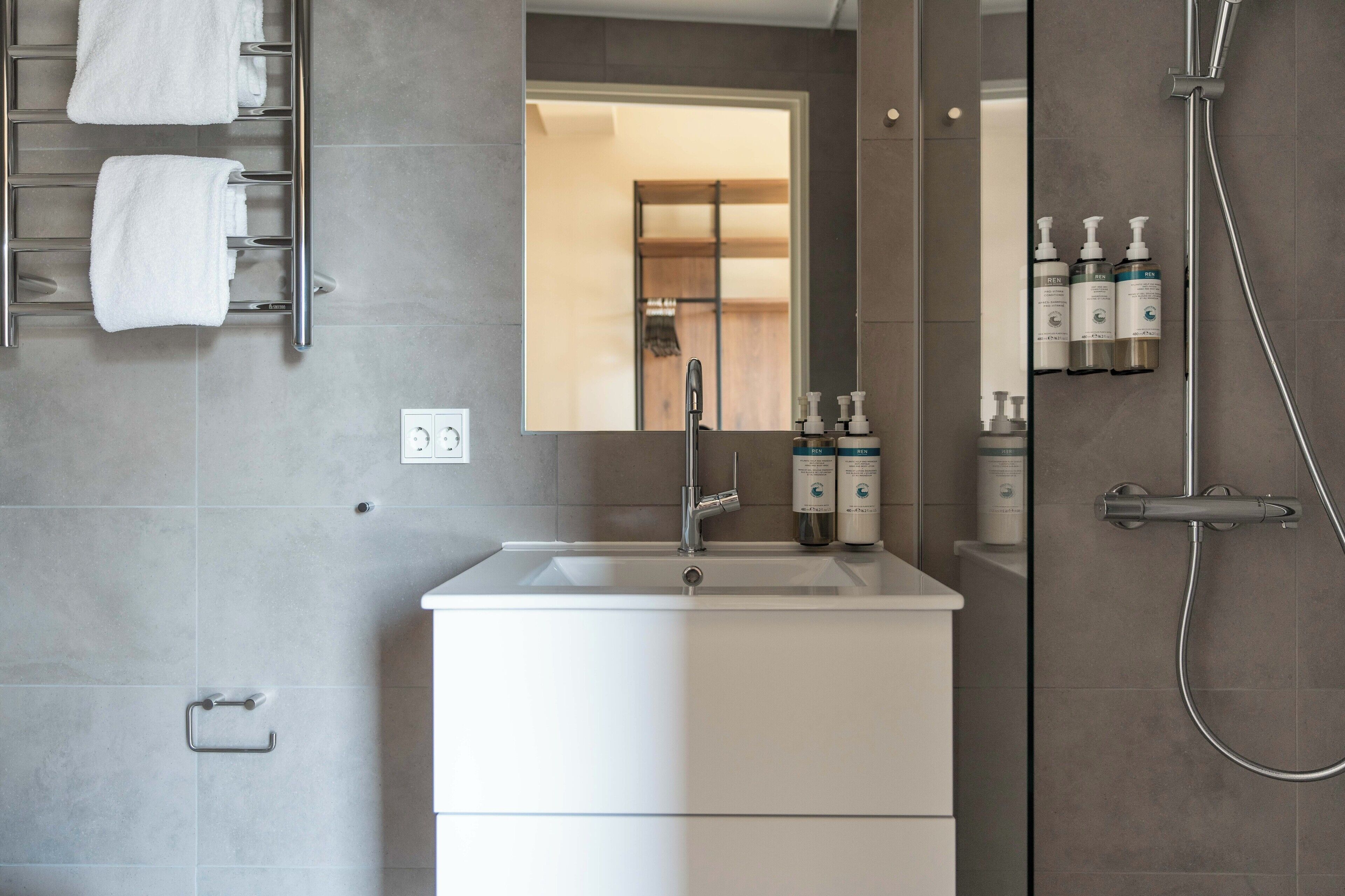 Une salle de bain moderne avec un lavabo blanc, un miroir et une douche.
