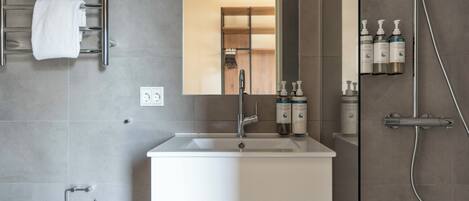 Une salle de bain moderne avec un lavabo blanc, un miroir et une douche.