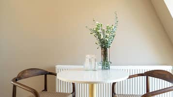 Una mesa redonda con dos sillas, un florero con flores y dos botellas sobre la mesa.