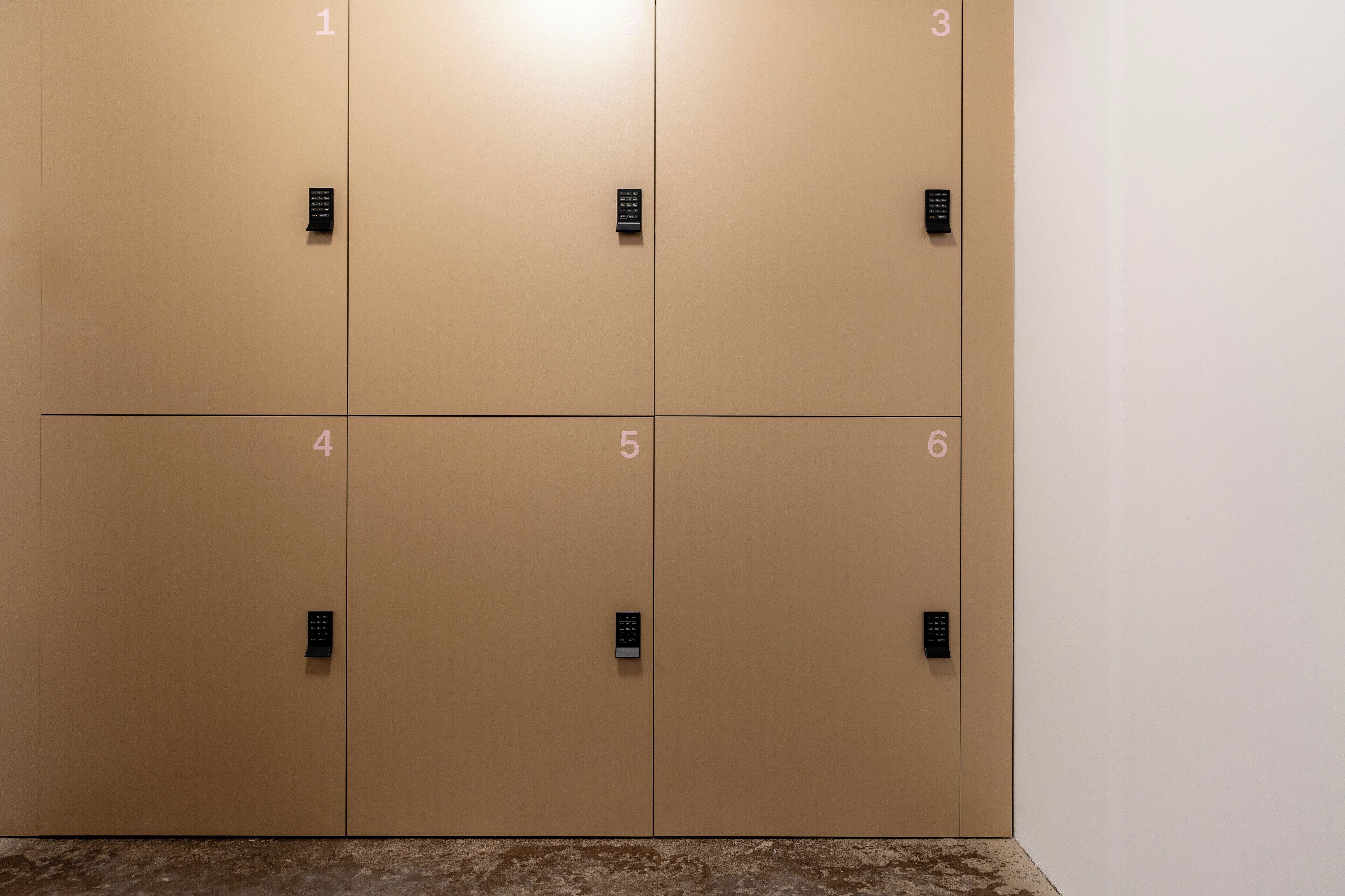 A row of six beige lockers with numbered doors, each with a black electronic lock.