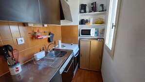 Cocina compacta con pileta, microondas y un mueble pequeño.