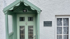 Una cabaña verde con un cartel con el número 61 sobre la puerta y un letrero debajo que dice 'Cabaña Acogedora No. 61'.