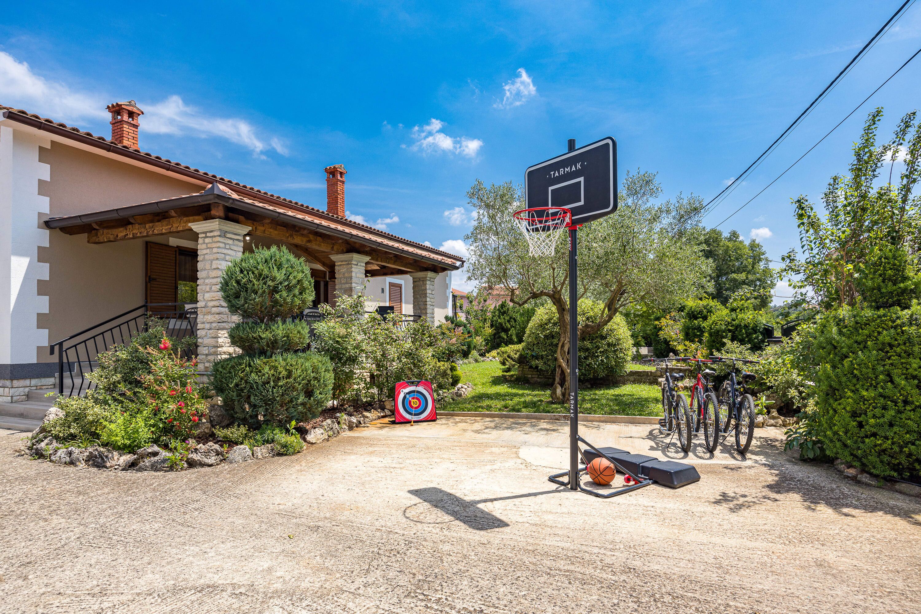 Un terrain de basket avec un panier, une cible et des vélos garés à proximité.