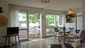 A spacious living area with a television, a chandelier, and a dining table with chairs. - T2 50m from beach with pool, pets allowed, private parking (Argelès-sur-Mer)