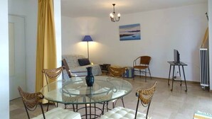 A living room with a glass dining table, cushioned chairs, a sofa, a lamp, and a painting on the wall. - T2 50m from beach with pool, pets allowed, private parking (Argelès-sur-Mer)