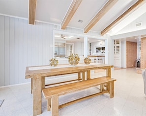 Una cocina moderna con armarios blancos, un banco de madera y flores decorativas sobre la mesa.