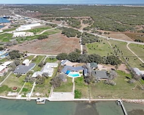 Vista aérea de una zona residencial con casas, piscina y un muelle junto al agua.