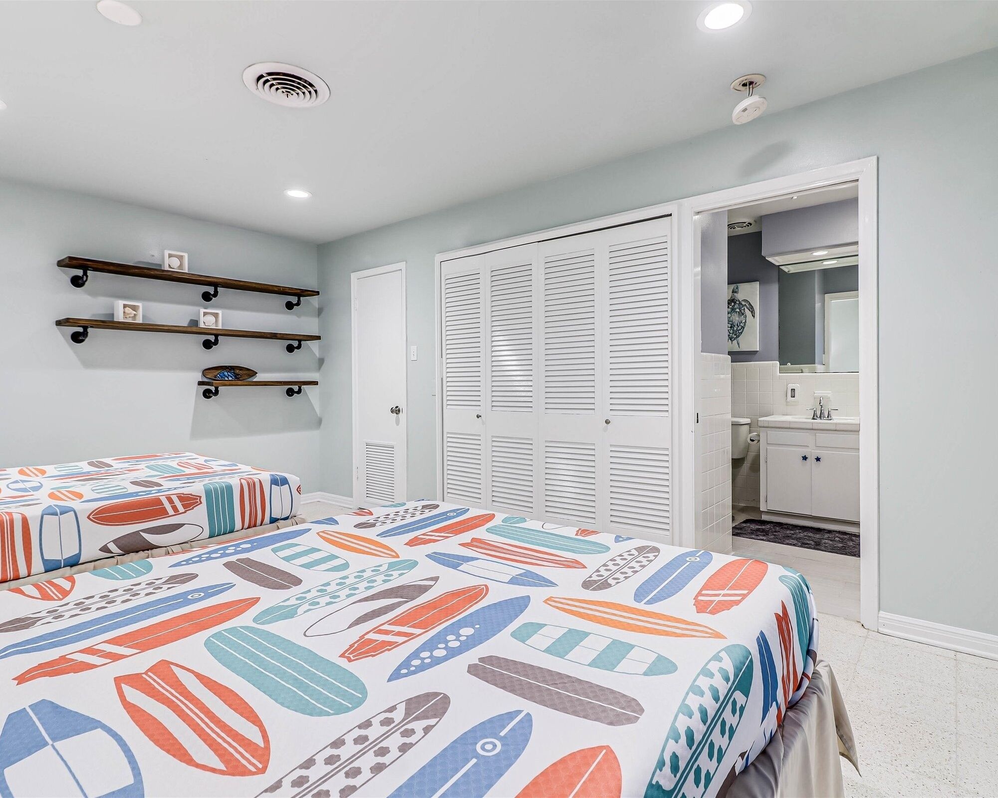 A bedroom with two beds, a closet, a bathroom, and a hallway.